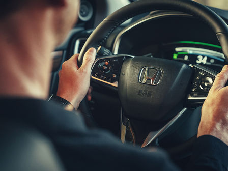 Gros plan de l'intérieur du véhicule avec le volant de direction du Honda CR-V Hybrid.