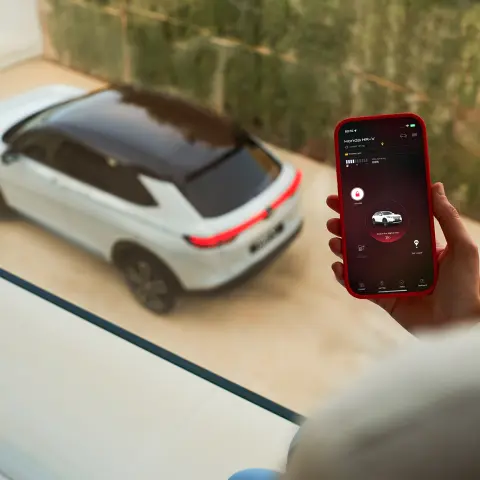 Gros plan d’une personne utilisant l’application My Honda + sur son téléphone avec la fenêtre extérieure du Honda HR-V