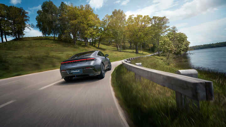 Plan arrière d'une Honda Prelude Hybride roulant sur une autoroute, à côté d'un lac.