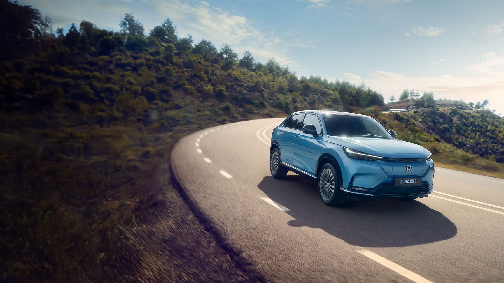 Vue de trois quarts avant de la Honda e:Ny1 traversant une montagne. 