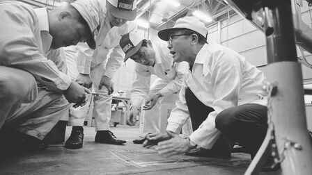 Soichiro Honda et des ouvriers en salopette blanche.