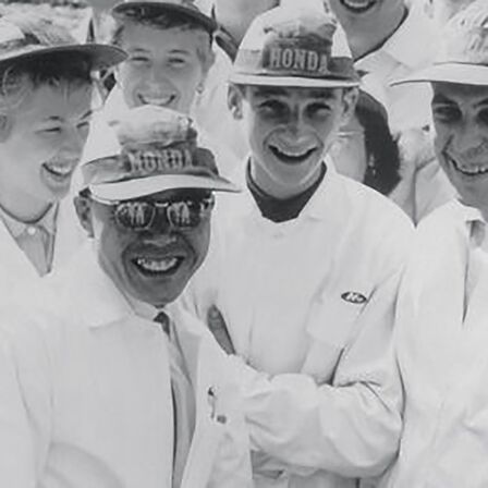 Soichiro Honda et des ouvriers en salopette blanche.