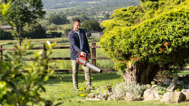 Utilisateur avec un souffleur à batterie dans un jardin