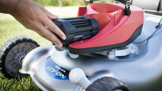 Model using Honda cordless leaf blower in garden location.