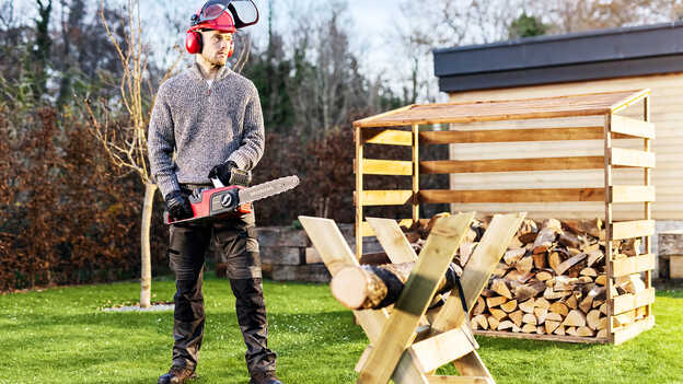 Une tronçonneuse à batterie HONDA dans un jardin.