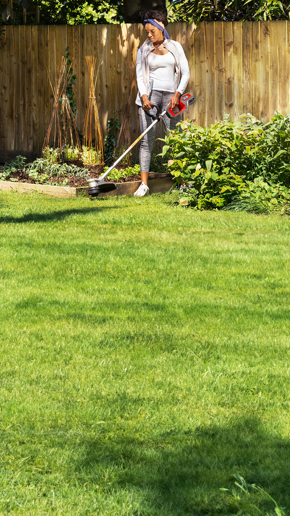 Utilisateur avec une tondeuse batterie Honda dans un jardin.