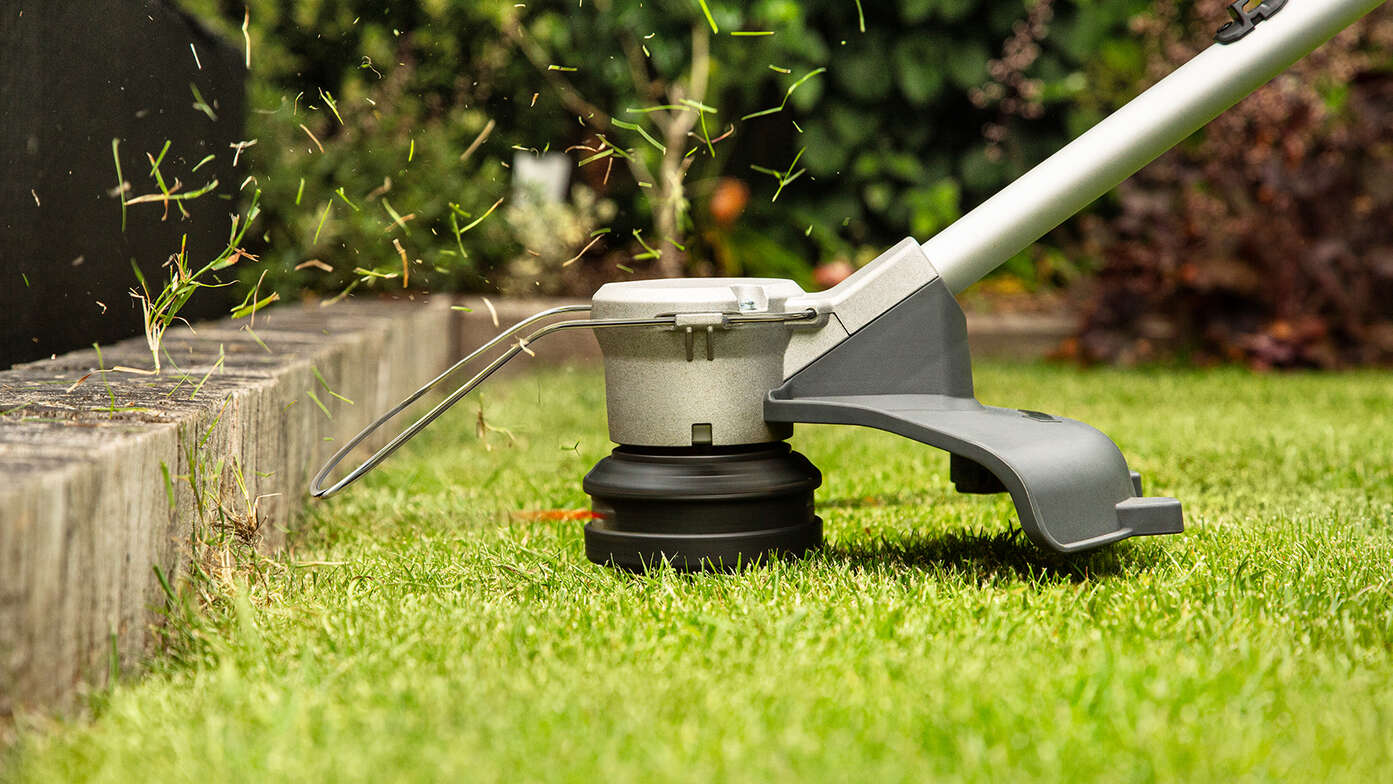 Coupe-bordure batterie Honda coupant de l'herbe sur le côté d'un jardin.