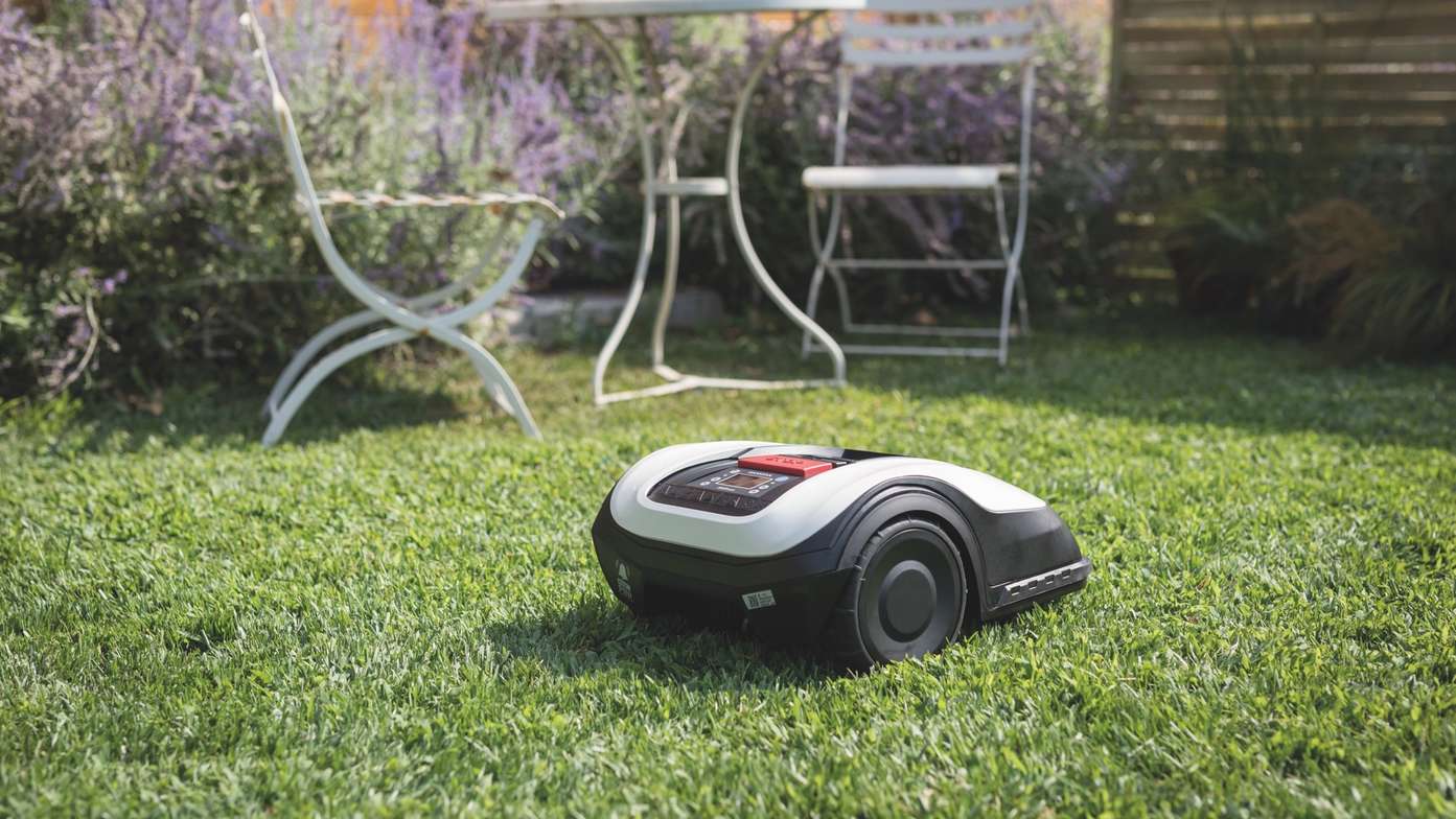 Vue de trois quarts arrière de la Honda Miimo dans un jardin avec une table et des chaises en arrière-plan.