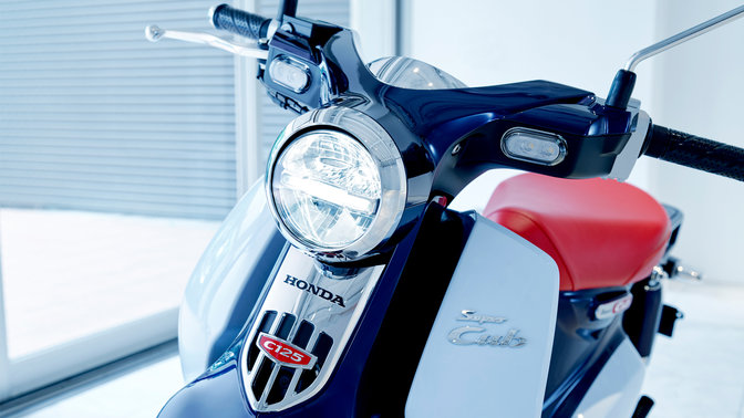 Honda Super Cub, garée dans un environnement moderne.
