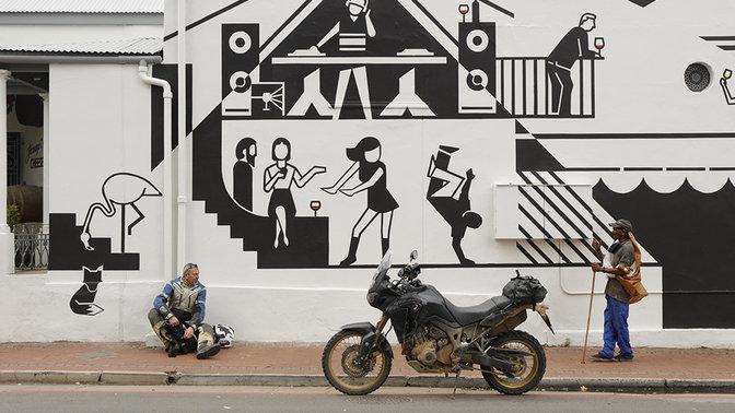 Pilote stationné, assis près d'un mur de street art.