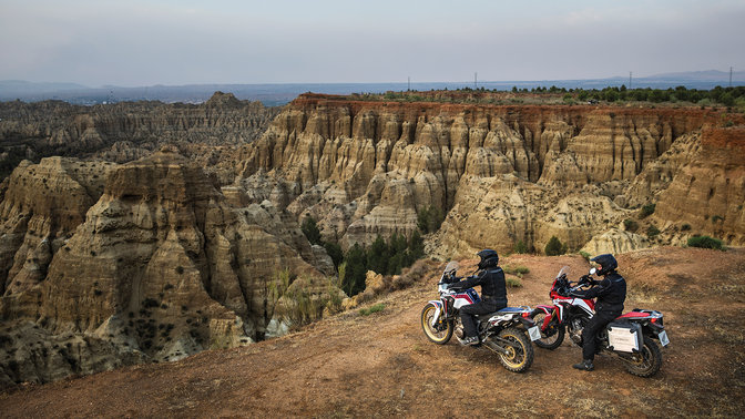 Deux Honda Africa Twin et leurs pilotes, face à un canyon.
