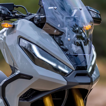 Vue de trois quarts avant droit de la Honda X-ADV, grise, avec pilote, à l'arrêt