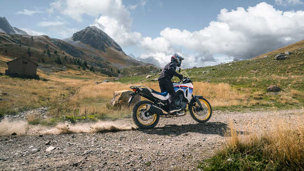 Cliché du Transalp en mouvement vu de derrière avec motard sur gravier