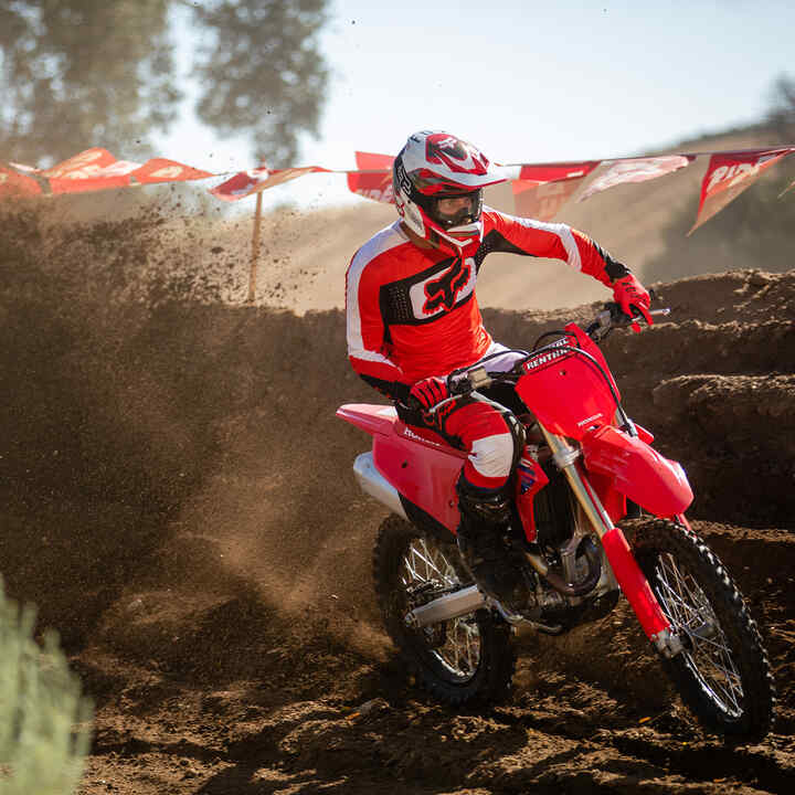 Motocross Honda CRF450R Cadre Rouge conduite en mode tout-terrain avec des montagnes en arrière-plan.