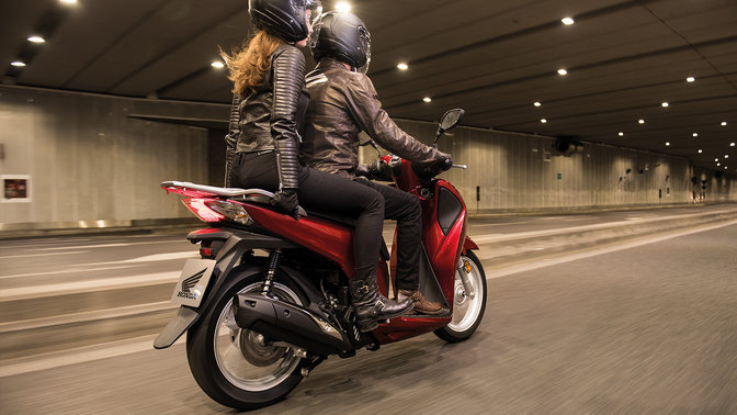 Prise de vue lat&eacute;rale de 2 mod&egrave;les conduisant la moto dans un tunnel
