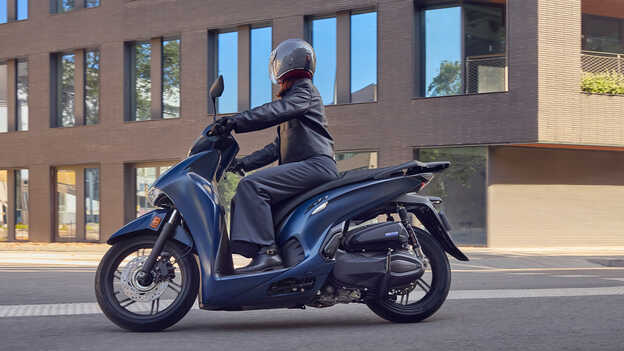 Motard sur un Honda SH350 de profil en ville.