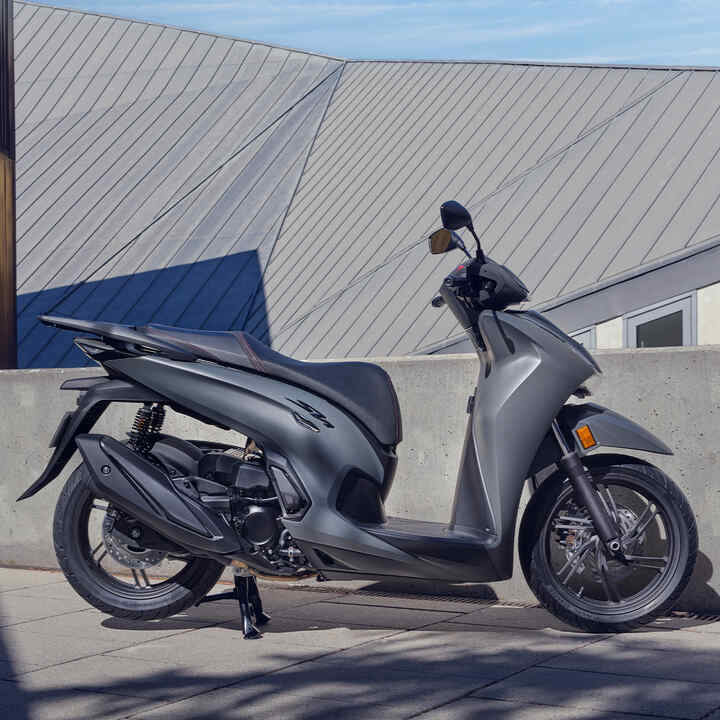 Honda SH350i à l’arrêt; de profil dans une cour.