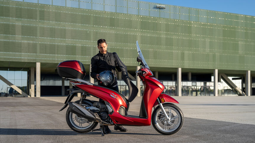 Vue de trois-quart avant droit du Honda SH350i, rouge, avec pilote, sur la route