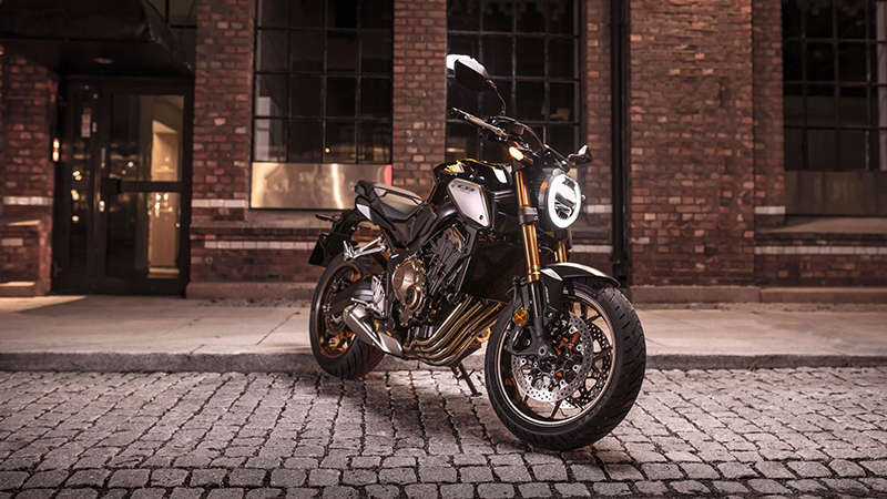 Vue de trois quarts avant droit du Roadster Honda Permis A2 CB650R Neo Sports Café, la nuit dans un paysage urbain