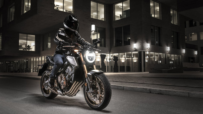 Vue de trois quarts avant droit du Roadster Honda Permis A2 CB650R Neo Sports Café, piloté de nuit dans un paysage urbain